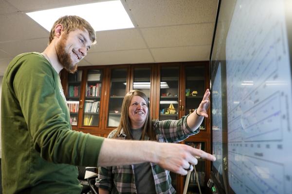 一名学生和一名工作人员正在看智能板上的图表