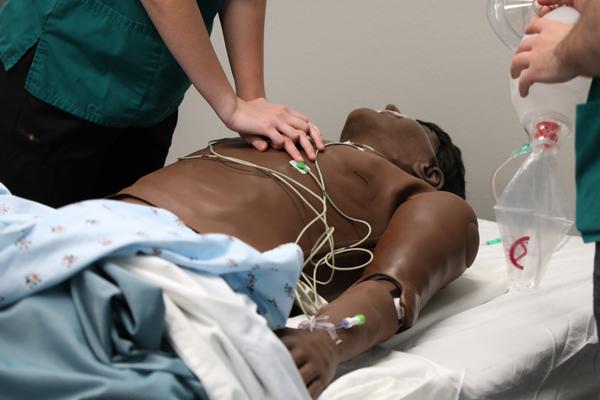 Nursing students performing respiratory procedures on a mannequin
